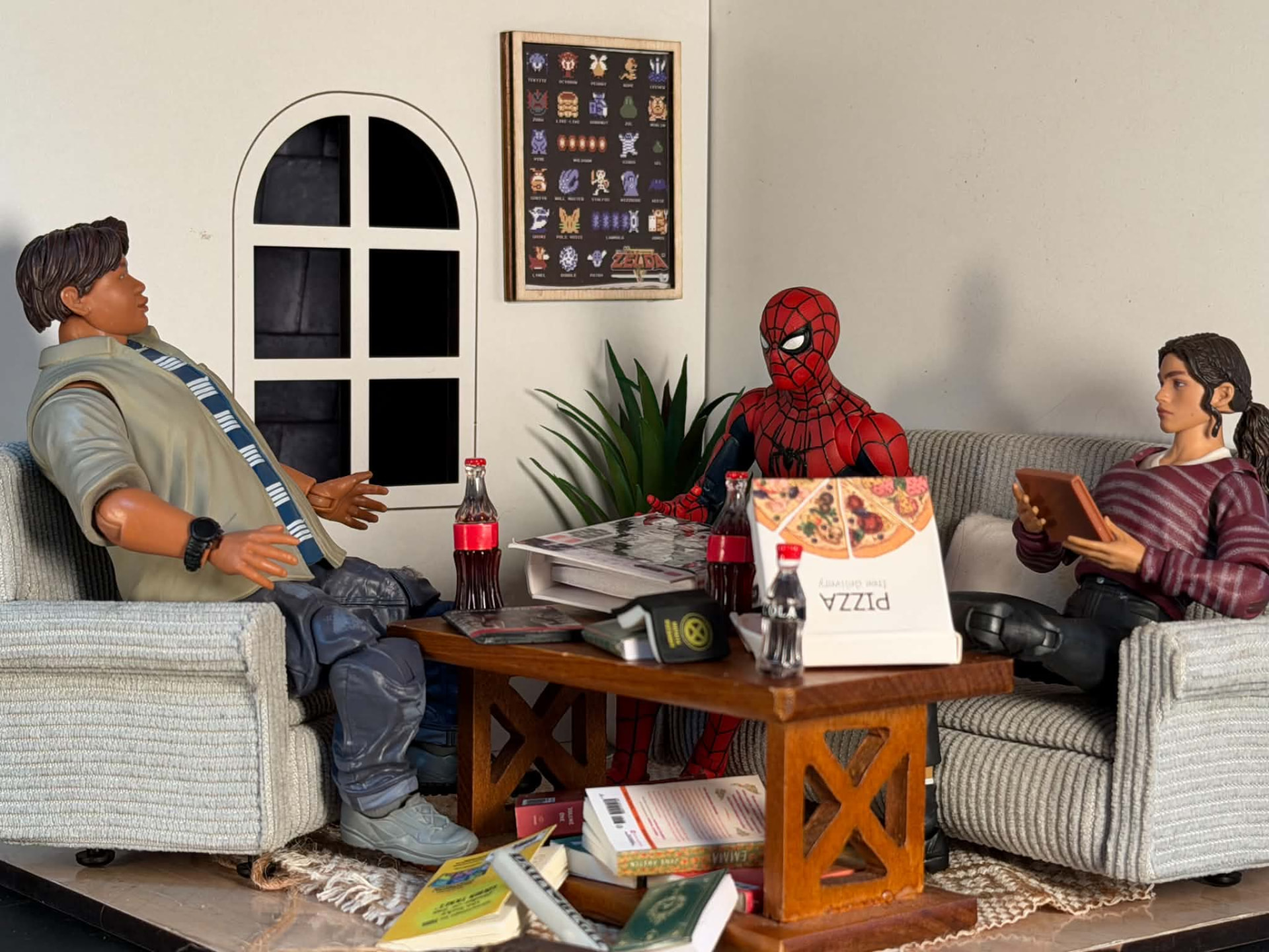 A living-room diorama with figures lounging around pizza boxes and soda bottles