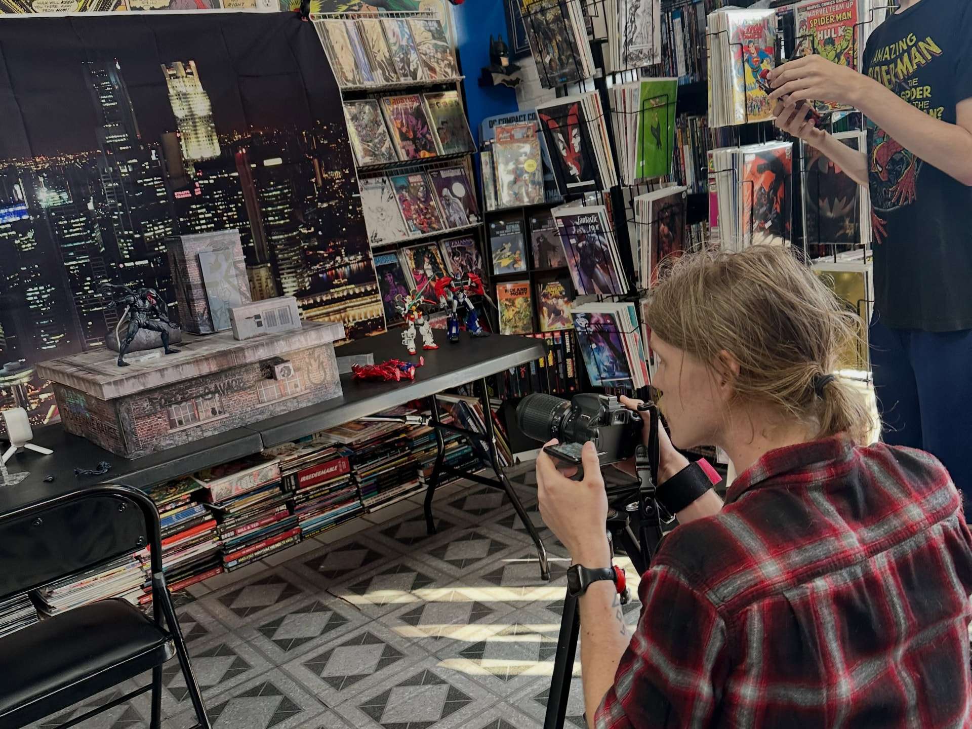 A collector photographing figures against a city backdrop at the shop